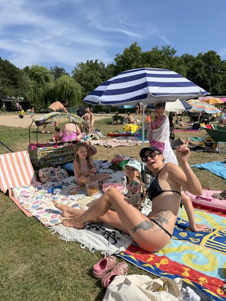 This vibrant photo captures a lively summer day at Haarweg, Vuren, with many people relaxing on blankets and towels under a bright blue sky
